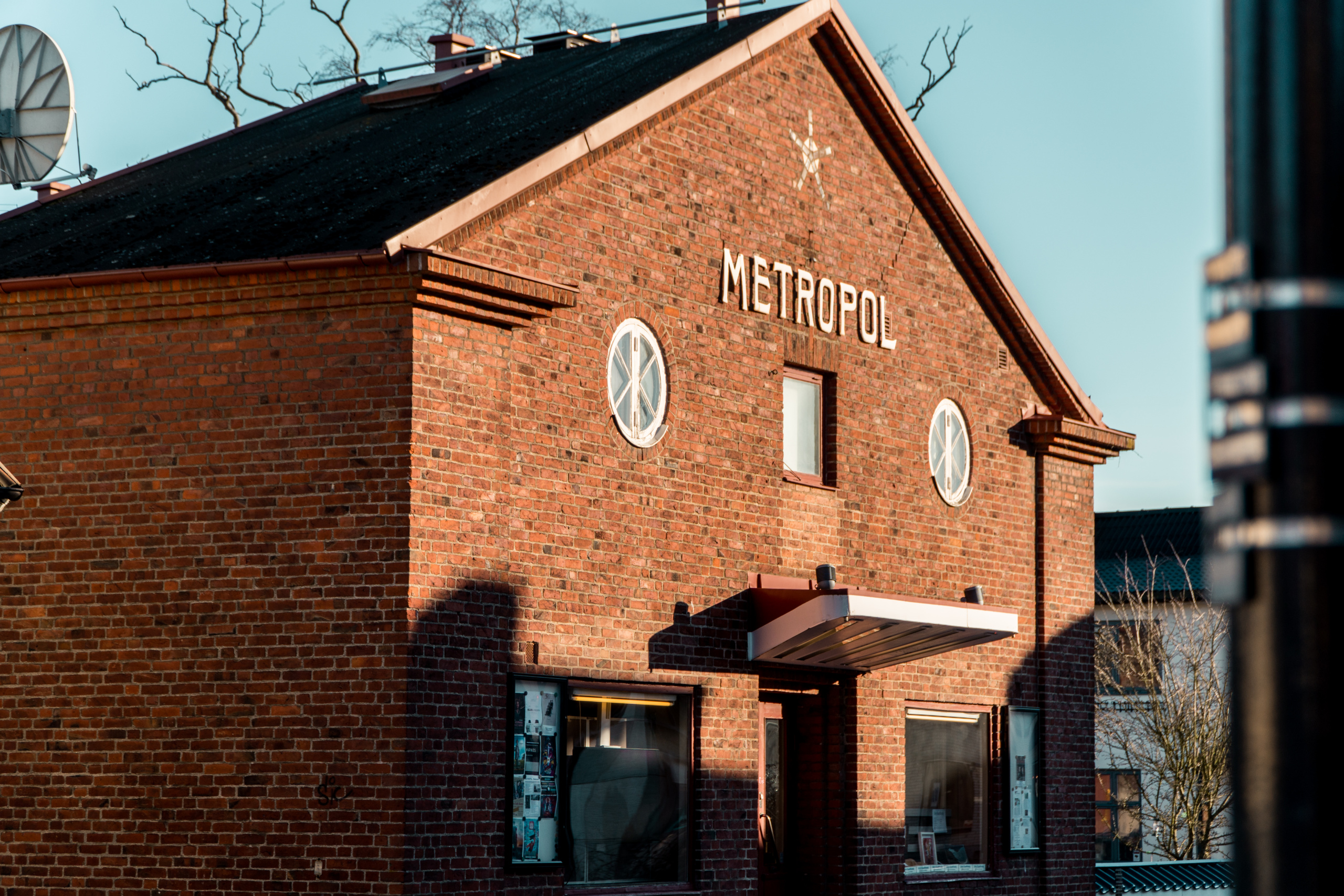 Röd tegelbyggnad i solsken. "Metropol" står ovanför huvudingången.