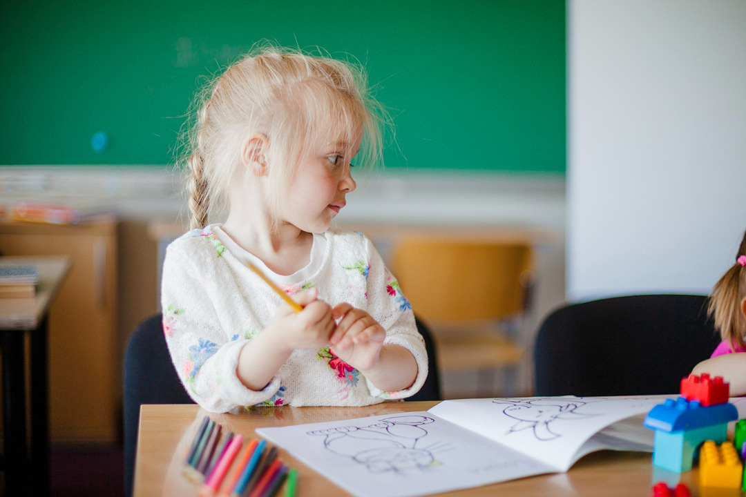 liten flicka som sitter vid en skolbänk