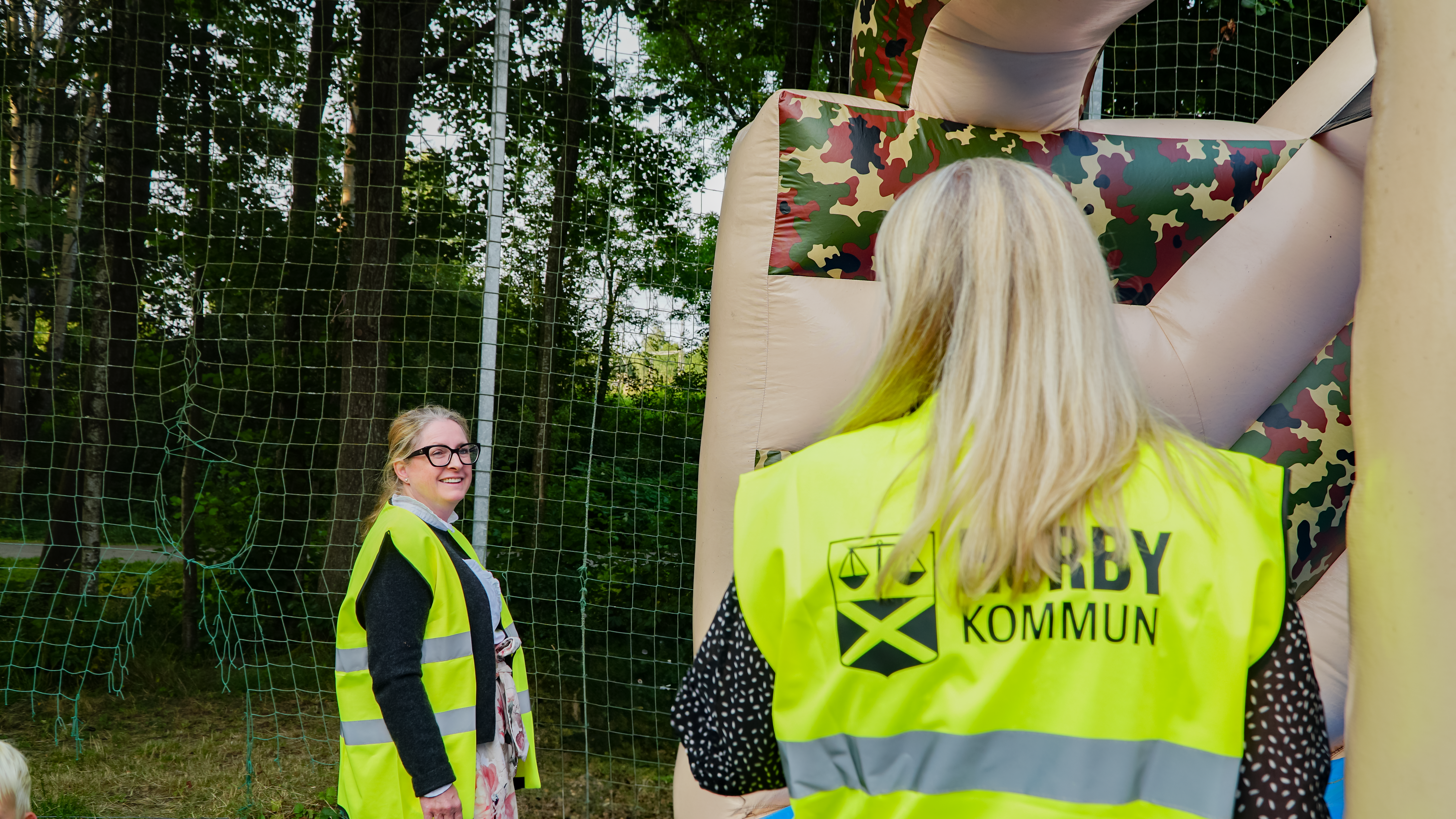 Kommundirektören och kommunikationschefen, iklädda kommunens gula västar, vaktar hoppborgen så att inget barn skadar sig.