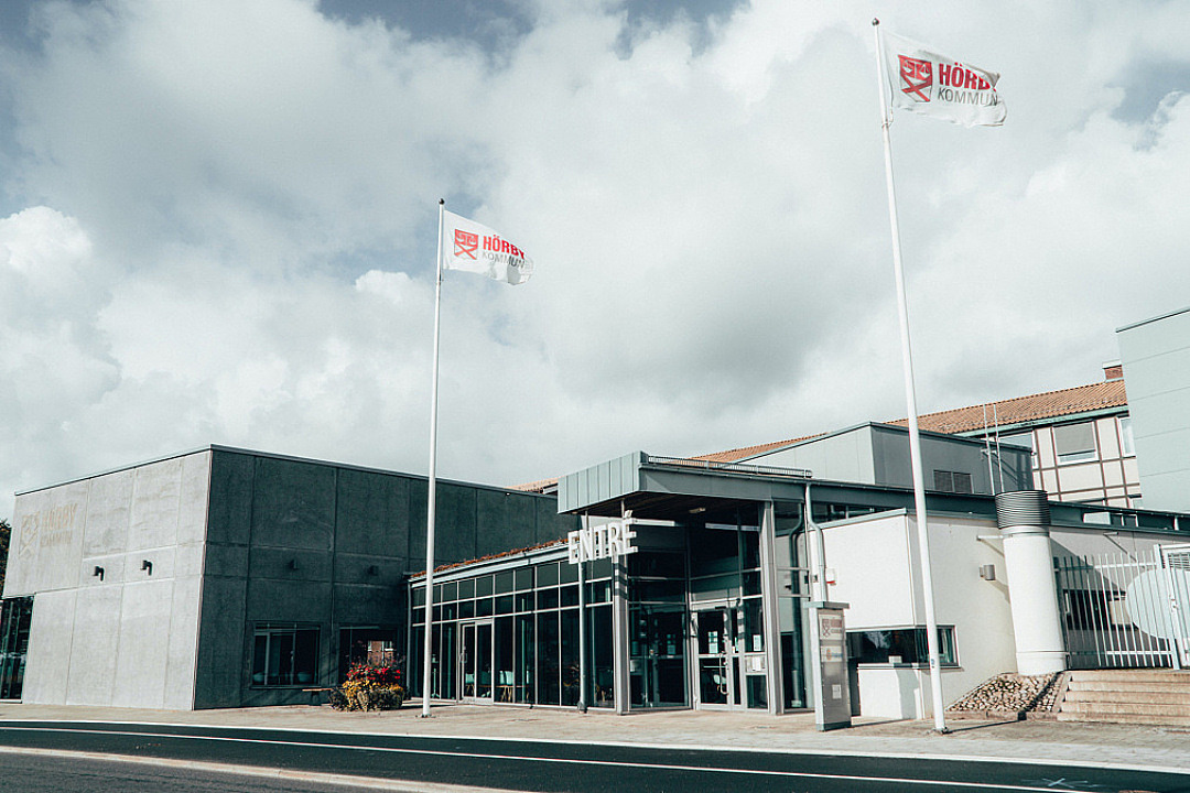 kommunhuset utifrån två flaggor med kommunlogga