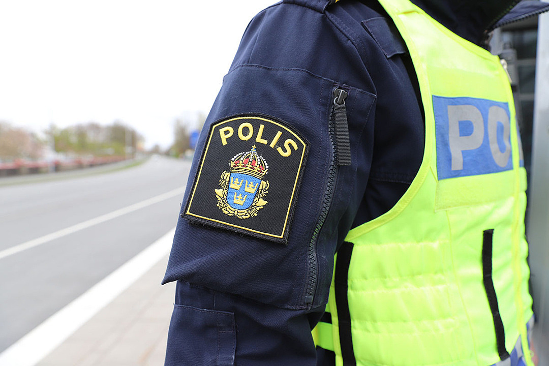 Halvbild på polisuniformerad person med polisemblem i fokus.