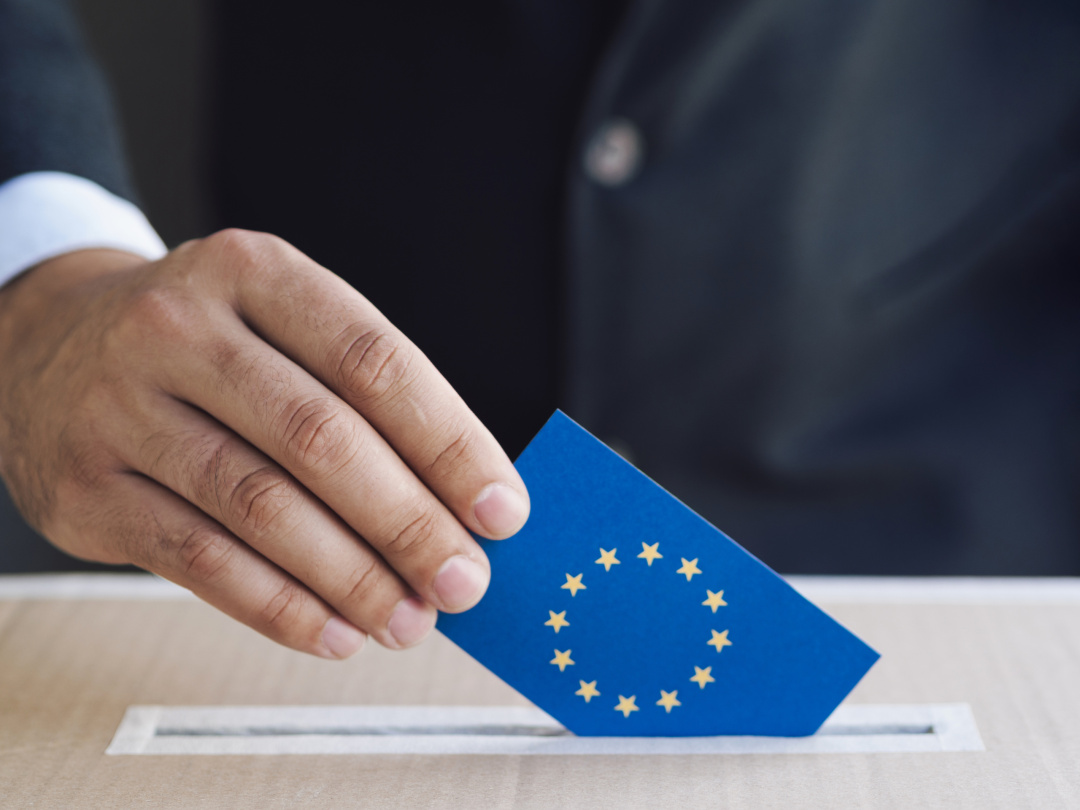 Man stoppar ett röstkort med EU-flaggan i en urna