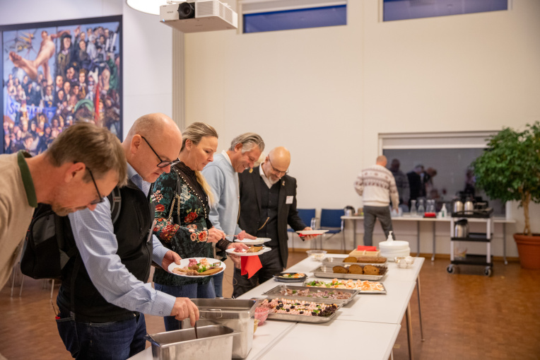 Människor som står i kö för att ta mat från ett bord som står uppdukat.