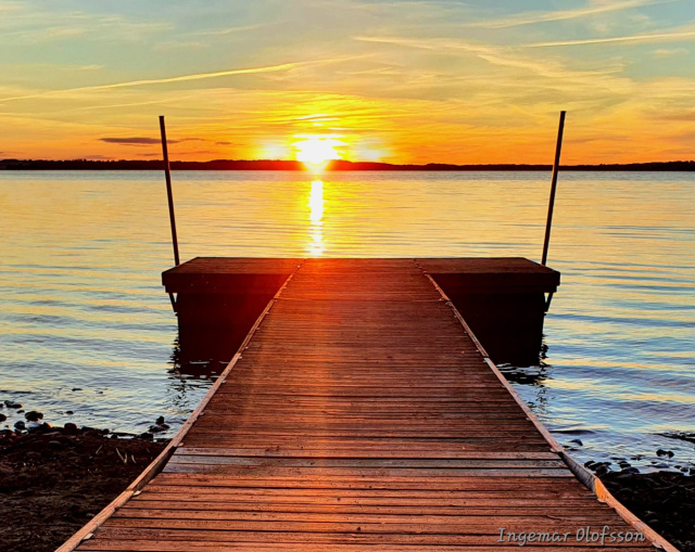 Brygga vid sjö i solnedgången.