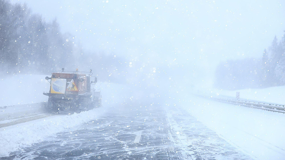 snöröjningstraktor på väg i snöoväder.